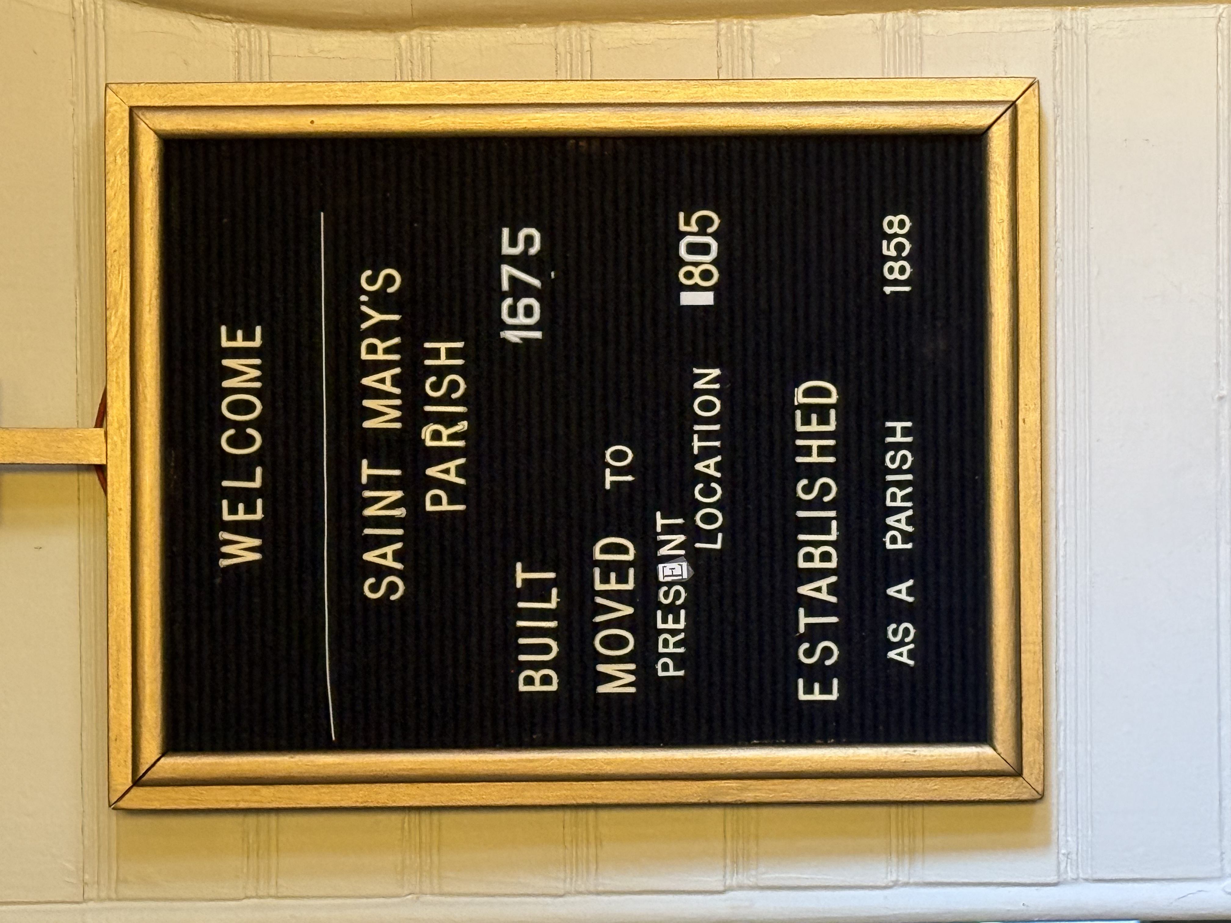 Gold-framed welcome letterboard noting the parish was built in 1675 and established in 1858