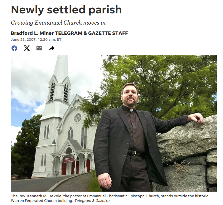Father Kenneth DeVoie standing beside a stone wall outside the historic white-steepled church building on the hill in Warren, Massachusetts.